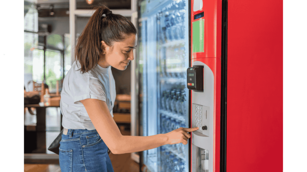 Staff retrieving snacks and beverages from a modern office vending machine