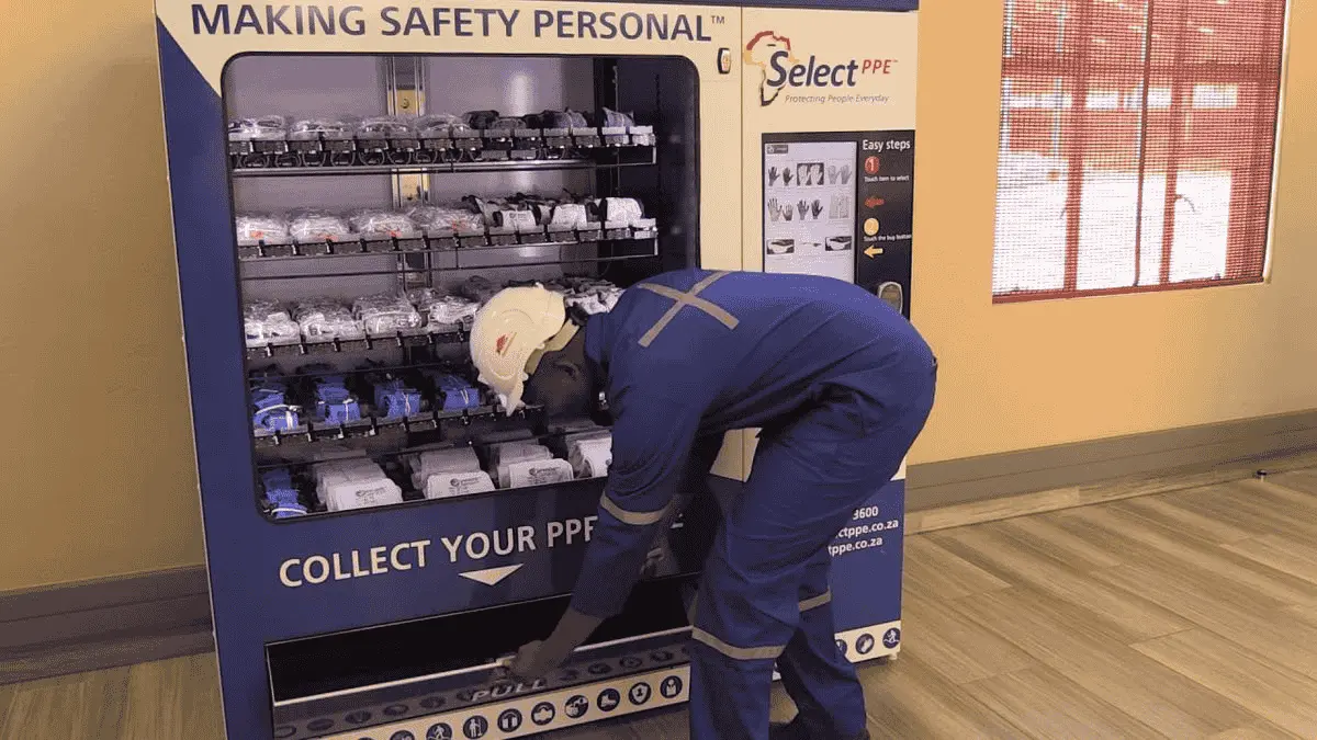 Worker collecting gloves from vending machine